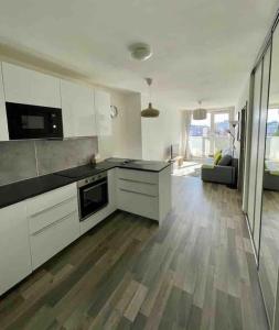 a kitchen with white cabinets and a living room at New apt in new building located begin of Petrzalka in Bratislava