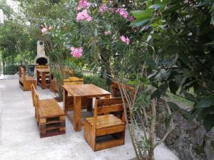 a row of wooden tables and benches with pink flowers at VILA RENATA in Grižane