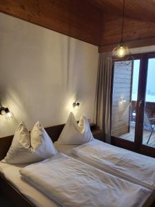 1 dormitorio con 1 cama con sábanas y almohadas blancas en Ferienhaus Koch Weißbriach en Weissbriach