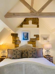 a bedroom with a white bed with a stone wall at Campden Mews in Chipping Campden