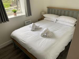 Una cama blanca con dos toallas encima. en Dondie's House, Kilchoan en Kilchoan