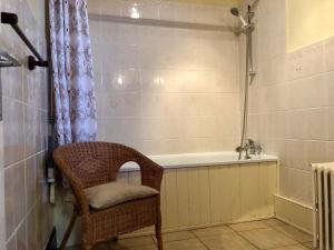 W łazience znajduje się wiklinowy fotel i wanna. w obiekcie Chavasse House, Chavasse Farm, Somme w mieście Hardecourt-aux-Bois