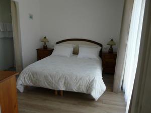 a bedroom with a bed with white sheets and pillows at Maison indépendante et privative 52m2 au calme in Cléré-les-Pins