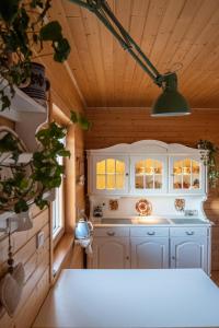 a kitchen with white cabinets and a green light at Alemiło - uroczy dom z balią i widokiem na Babią Górę in Zawoja