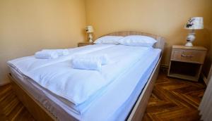 a large white bed with white sheets and pillows at Flower Apartment - Deluxe in Odorheiu Secuiesc