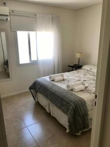1 dormitorio con 1 cama con 2 almohadas y ventana en Departamentos Dorrego en Mendoza