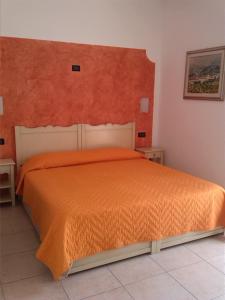 a bedroom with a bed with an orange bedspread at Agriturismo ai Ciliegi in Bardolino