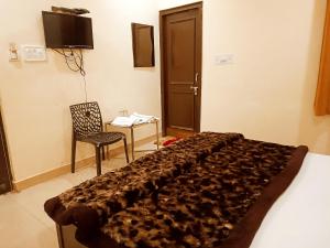 a bedroom with a bed and a chair and a table at Hotel Orange Classic in Rishīkesh