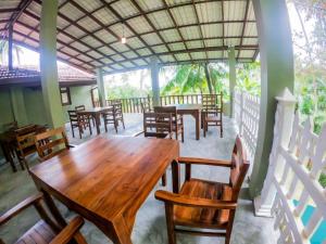 une salle à manger avec des tables et des chaises en bois dans l'établissement Red Sun Beach Villa Kosgoda, à Kosgoda