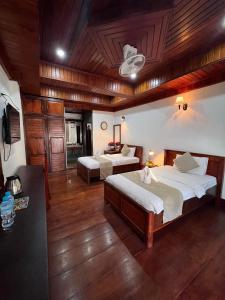 a large room with two beds and a television at Chaluenxay Boutique hotel in Luang Prabang