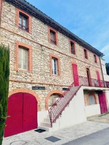 un edificio de ladrillo con puertas rojas y garaje rojo en Appartement au calme au milieu du vignoble de Gigondas, en Gigondas