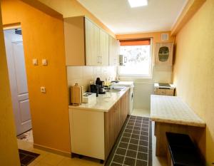 een keuken met gele muren, witte werkbladen en een raam bij Flower Apartment - Standard in Odorheiu Secuiesc