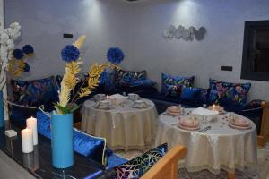 un comedor con 2 mesas y sofás azules en Moonrise Villa VIP Midelt en Midelt