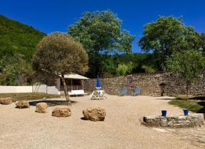 a patio with rocks and a table and a blue umbrella at Gite le Roucayral , vue imprenable sur St Cirq Lapopie, deux chambres climatisées in Tour-de-Faure