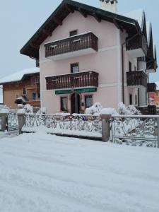 un bâtiment recouvert de neige devant une clôture dans l'établissement Alloggio Turistico Bufera, à Roana