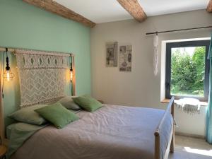 una camera da letto con un letto con cuscini verdi e una finestra di Le Mas Saint Philippe a Jonquières