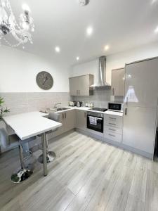 a kitchen with white cabinets and a table in it at Elysium Liverpool in Liverpool