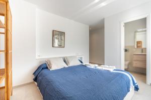 a white bedroom with a blue bed and a bathroom at Lovely Central Apartment Guillem 3 Bedrooms Close To The Beach in Cala de Sant Vicent