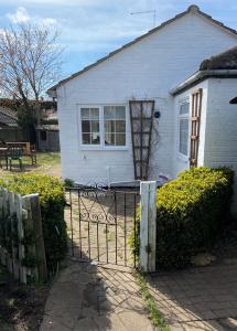Uma casa branca com um portão à frente. em Field Cottage em Whittlesey