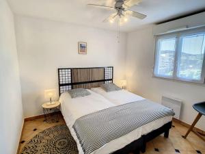 ein Schlafzimmer mit einem Bett und einem Deckenventilator in der Unterkunft Port Marine - T3 calme, avec terrasse, piscine, près de la plage in Sainte-Maxime