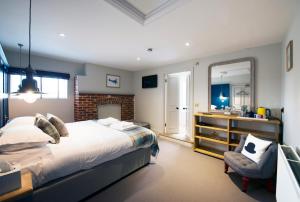 a bedroom with a bed and a mirror and a chair at The Coach House in Potton