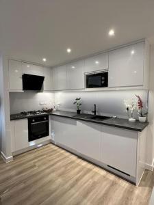 a kitchen with white cabinets and black counter tops at Sea View Apartment Poole Quay - FREE Parking in Poole