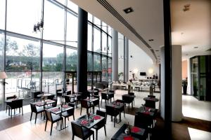 ノーラにあるHoliday Inn Nola - Naples Vulcano Buono, an IHG Hotelのテーブルと椅子、大きな窓のあるレストラン