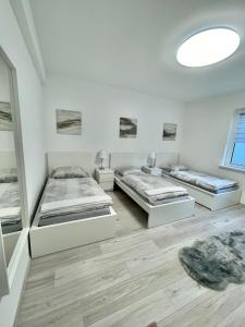 3 Betten in einem Zimmer mit weißen Wänden und Holzböden in der Unterkunft Elite Rooms - Netflix - Coffee - WiFi - City in Wuppertal