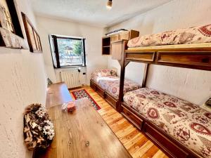 a room with two bunk beds and a wooden table at Chalet le Pigne Gressoney Saint Jean in Gressoney-Saint-Jean
