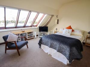 a bedroom with a bed and a chair and a tv at Meadow Place in Ipstones
