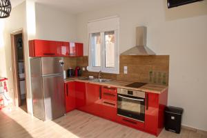 a kitchen with red cabinets and a stainless steel refrigerator at Lila's villa maisonette with private pool in Nerotriviá