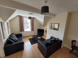 a living room with two black couches and a television at Spacious cosy apartment in Llandudno