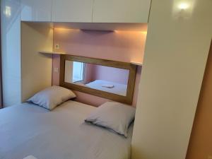 a small bedroom with a bed with a mirror at Evasion Paris-Disney in Noisy-le-Grand