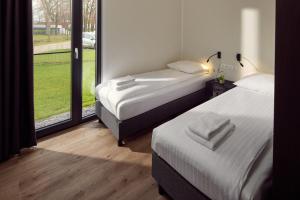 two beds in a room with a large window at Hofparken De Bergvennen in Lattrop