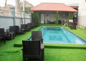 einen Pool mit Stühlen auf dem Rasen neben einem Gebäude in der Unterkunft BOSS HOTELS & SUITES***** in Lagos