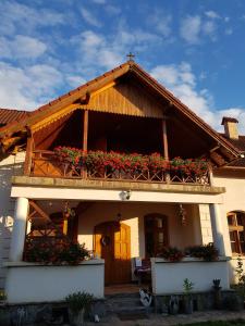 a house with a balcony with flowers on it at Enikő Vendégház in Cernatu de Sus