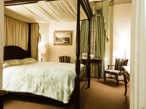 um quarto com uma cama de dossel e uma secretária em The Guest House Historic Mansion em Natchez