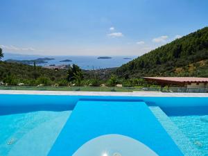 a blue swimming pool with a view of the ocean at Sky Sea Resort & Villas in Skiathos