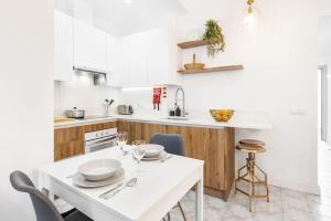 a white kitchen with a white table and chairs at RG Casa do Carmo in Faro