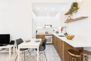 a white kitchen with a white table and chairs at RG Casa do Carmo in Faro