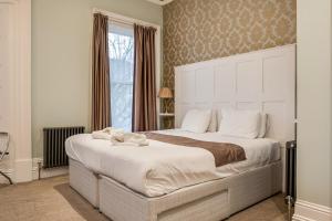 Central Belfast Apartments Harpers في بلفاست: غرفة نوم مع سرير أبيض كبير مع نافذة كبيرة