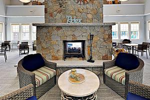 un vestíbulo con una chimenea de piedra con 2 sillas y una mesa en Cape Arundel House, en Kennebunk