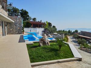 un patio trasero con piscina y una casa en Sky Sea Resort & Villas en Skiathos