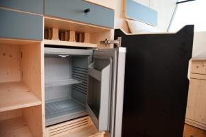 einen leeren Kühlschrank in einer Küche mit Holzschränken in der Unterkunft Sleep Space 21 - Green Tiny Village Harz in Osterode