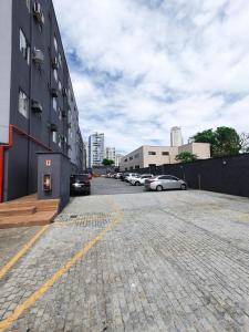 un estacionamiento con autos estacionados al lado de un edificio en Avenida Palace Hotel, en Joinville