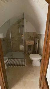a bathroom with a toilet and a glass shower at Trulli Antichi Mestieri - Widespread Trulli in the historic center in Alberobello