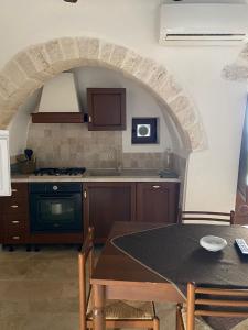 a kitchen with a table and a kitchen with an archway at Trulli Antichi Mestieri - Widespread Trulli in the historic center in Alberobello