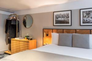 a bedroom with a bed and a dresser and a mirror at Victory House Leicester Square in London