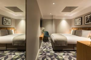a hotel room with two beds and a mirror at Victory House Leicester Square in London