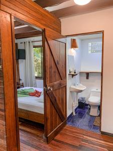 - Baño con dormitorio con cama y lavamanos en Cabinas Montesol, en Puerto Viejo